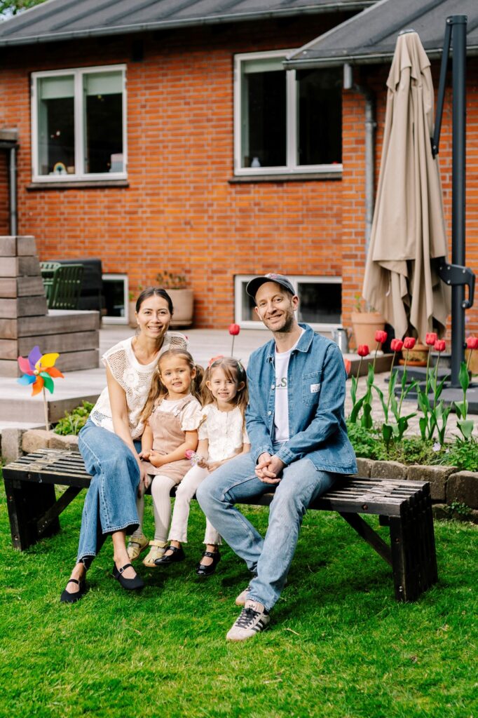 En familie sidder foran deres hus