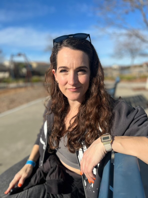 Jessica sidder på en bænk og kigger direkte på dig