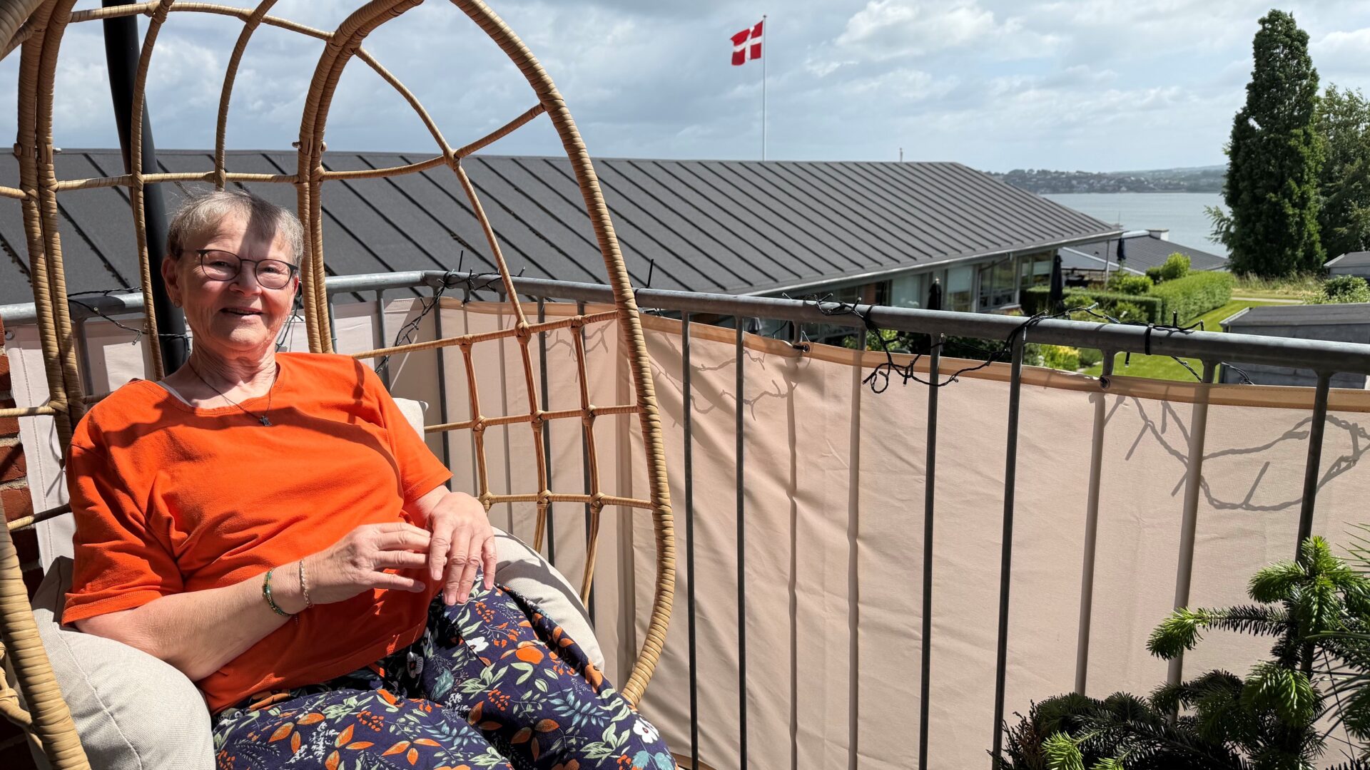 Gerthie Elsen sidder i en stol på sin altan med fjorden som baggrund
