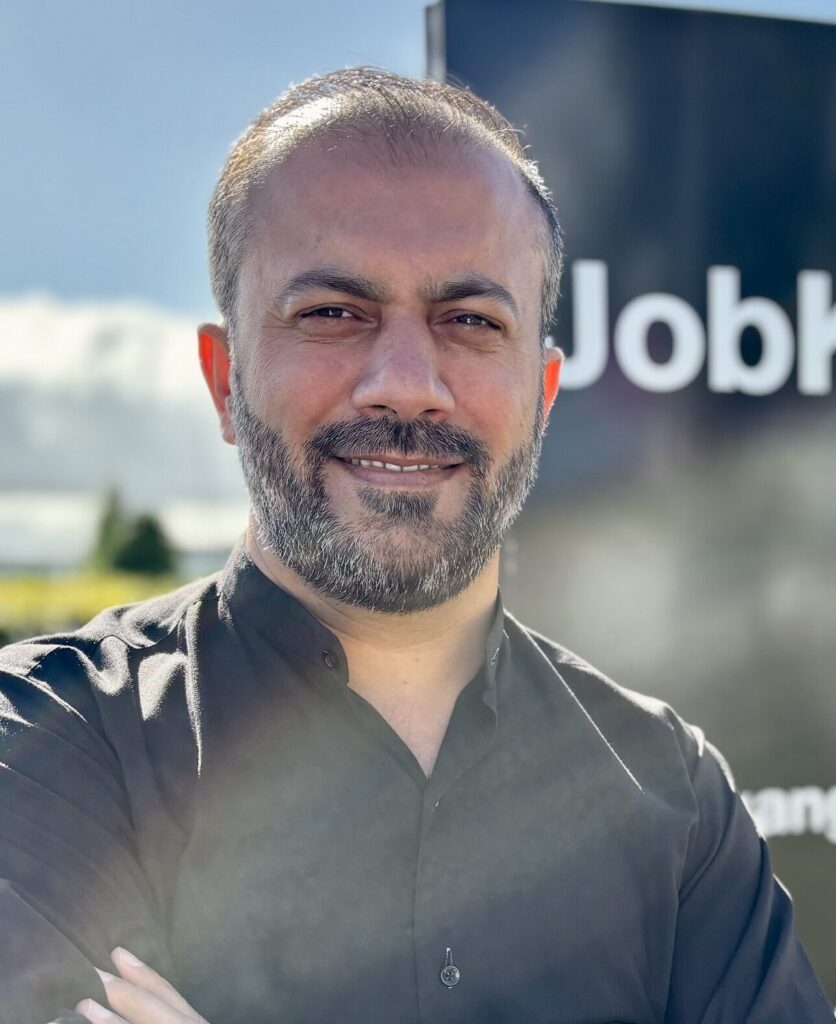 Mustafa Niazi står foran et skilt hvor der står Job Kolding