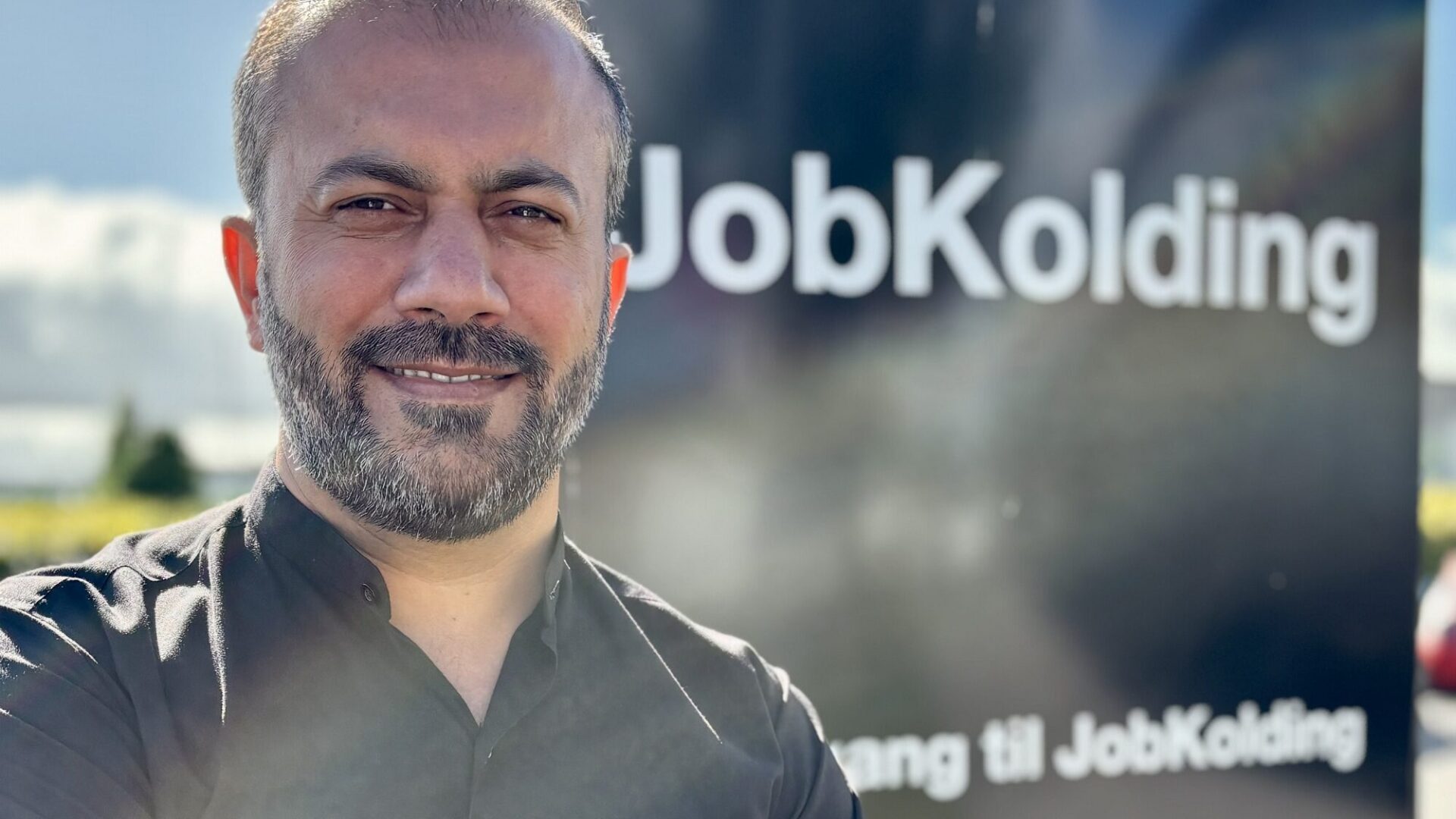 Mustafa Niazi står foran et skilt hvor der står Job Kolding
