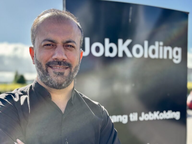 Mustafa Niazi står foran et skilt hvor der står Job Kolding