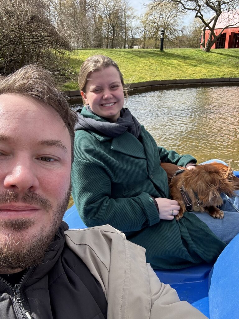 Anders og Clara sidder i en vandcykel i Legeparken i Kolding. Clara har deres hund på skøddet